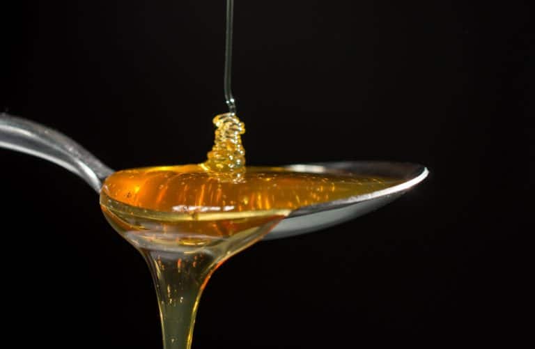 Miel liquide dans une cuillère : la fermentation du miel peut se produire dans le pot après récolte.